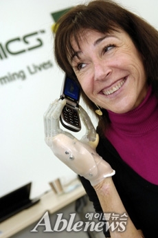 손목까지 오는 프로디짓 로봇 의수지를 착용 핸드폰을 사용하는 모습@touchbionics