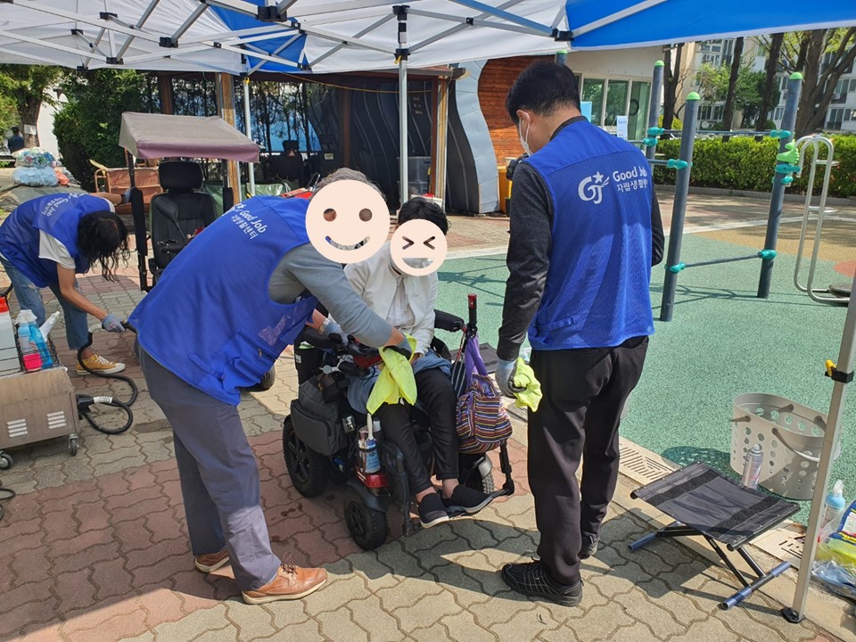 이용자가 탑승중인 전동휠체어를 닦는 모습