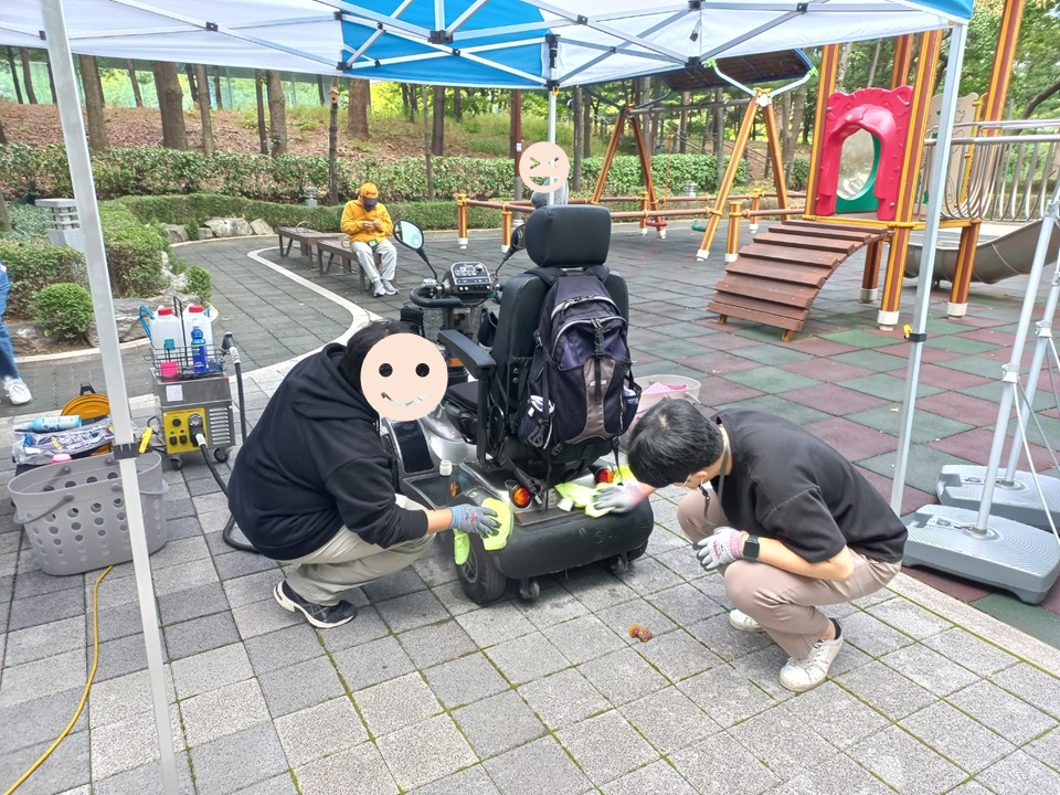 두 사람이 전동스쿠터의 물기를 제거하고 있는 모습